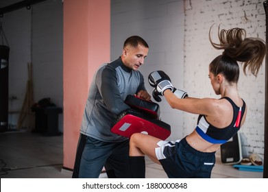 A Young Strong Kickboxer Girl Kicks Her Sparring Partner With A Boxing Paw In A Personal Training Session