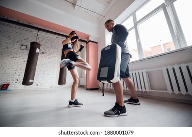 A Young Strong Kickboxer Girl Kicks Her Sparring Partner With A Boxing Paw In A Personal Training Session