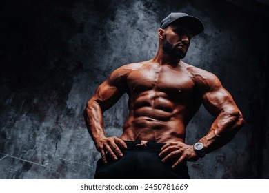 Young strong man bodybuilder in cap on stone wall background - Powered by Shutterstock