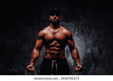 Young strong man bodybuilder in cap on stone wall background - Powered by Shutterstock