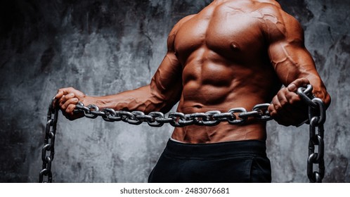 Young strong man bodybuilder with heavy chain on dark wall background - Powered by Shutterstock