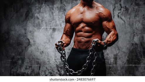 Young strong man bodybuilder with heavy chain on dark wall background - Powered by Shutterstock