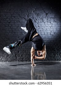 Young Strong Man Break Dance. On Dark Wall Background.