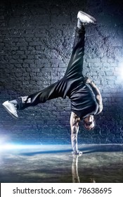 Young Strong Man Break Dance. On Dark Wall Background.