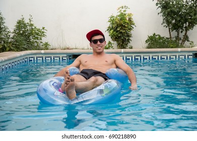 Young strong man on an air bed in the pool.  - Powered by Shutterstock