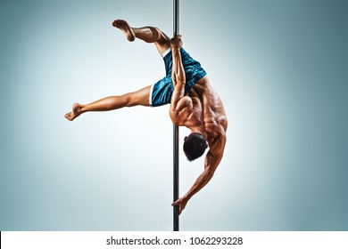 Young strong man pole dancing on blue and white background