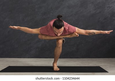 Young Strong Man Practicing Yoga, Standing In Flexible Pose On Mat In Fitness Class, Making Balance Exercise, Copy Space