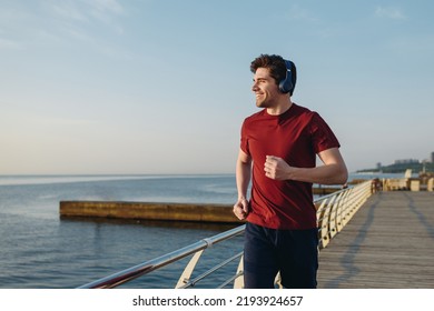 Young strong sporty athletic fit sportsman man wear sports clothes heapdhones listen music look aside warm up training at sunrise sun dawn over sea beach outdoor on pier seaside in summer day morning - Powered by Shutterstock