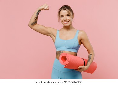 Young strong sporty athletic fitness trainer instructor woman wear blue tracksuit spend time in home gym show hand biceps muscles isolated on pastel plain light pink background. Workout sport concept