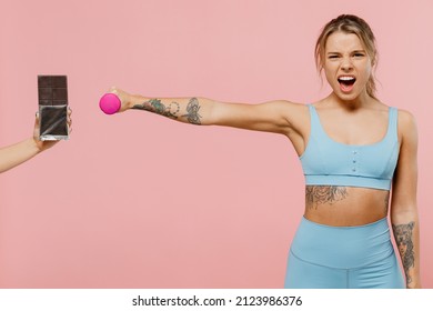 Young Strong Sporty Athletic Fitness Trainer Instructor Woman Wear Blue Tracksuit Spend Time In Home Gym Scream Reject Chocolate Hold Dumbbells Isolated On Plain Pink Background. Workout Sport Concept