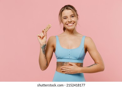 Young Strong Sporty Athletic Fitness Trainer Instructor Woman Wear Blue Tracksuit Spend Time In Home Gym Eat Snack Food Isolated On Pastel Plain Light Pink Background. Workout Sport Motivation Concept