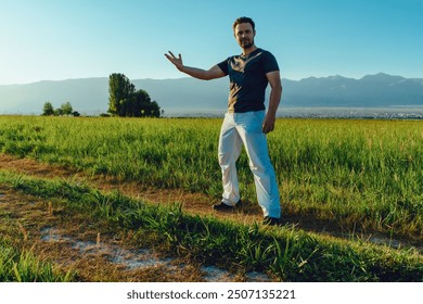 Young strong successful man posing in summer field on mountains background - Powered by Shutterstock