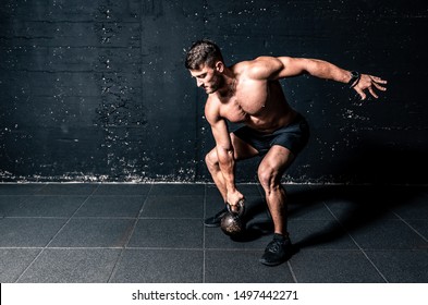 Young strong sweaty focused fit muscular man with big muscles holding heavy kettlebell for crossfit swing training hard core workout in the gym real people exercising - Powered by Shutterstock