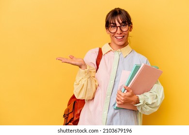 Young student Argentinian woman isolated on yellow background showing a copy space on a palm and holding another hand on waist.