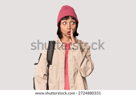 Young student with backpack and beanie in studio dreaming of achieving goals and purposes