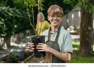 Young student boy holding fruit tree seedling. Kids taking care of school garden during outdoor sustainable education, class in forest school. Concept of experiential learning and ecoliteracy. - Powered by Shutterstock