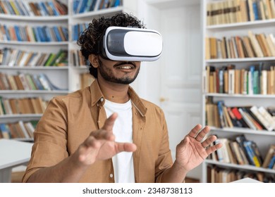 Young student close-up inside university academic library studying, man uses VR virtual reality glasses to watch course videos and online material.