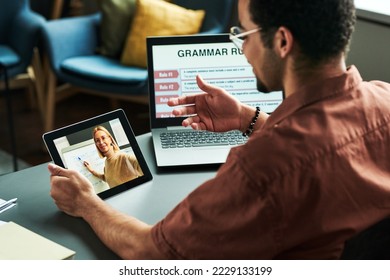 Young student communicating with teacher on tablet screen making presentation of new English grammar subject during online lesson - Shutterstock ID 2229133199