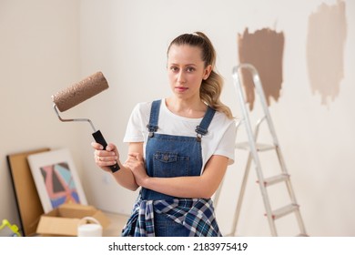 A Young Student Girl Stands In The Middle Of A Room Undergoing Renovation In Her Dorm Room. This Experience Is The First For Her. She Holds A Paint Roller In Her Right Hand.