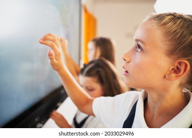 Young student girls interacting with digital blackboard