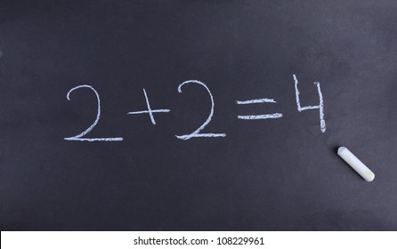 A young student has solved a basic math equation on a chalkboard.