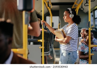 Young student is listening to music on her headphones while she's commuting