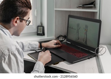 Young student male 3D designer uses graphics tablet to work at his desk. development of 3d characters for online games.