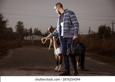 Young Student Man On His Vacation In Countryside Standing On The Road With Pony