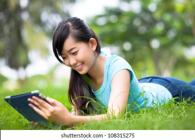 Young Student Reading Something On Tablet Outdoors