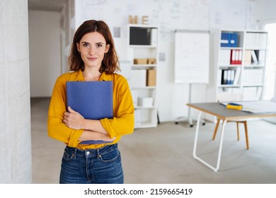 Young student stands in an office with her application documents and looks into the camera - Shutterstock ID 2159665419