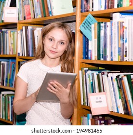 Young student using a tablet computer in a library