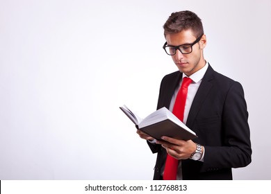 Young Student Wearing Glasses And Reading A Law Book On Grey Background