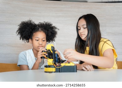 Young Students Controlling a Prototype with Joy, Friends Operating a Small Robotic Arm, Diverse Girls Learning Programming Through Remote Controller Game, Hands-on STEM Education