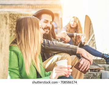 Young Students Drinking Coffee In Paper Ripley Cup Outdoor During A University Break - Cheerful Friends Toasting Cappuccino In Old Town Center - Focus On Bearded Man - Warm Filter