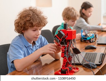 Young Students At Engineering Club. Boy Fixing An Arm Of A Robot. Afterschool Activity.