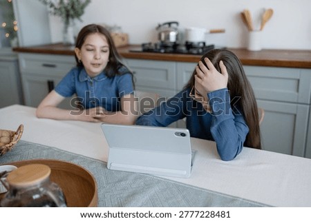 Young students frustrated at kitchen table struggling with homework assignments in cozy home. Frustrated, homework, kitchen, students, cozy, girls.
