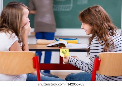 Young students laughing and holding smiley note during the class - Powered by Shutterstock