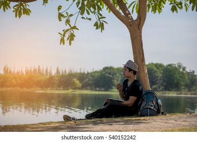 Young students Reading under a tree on the waterfront.