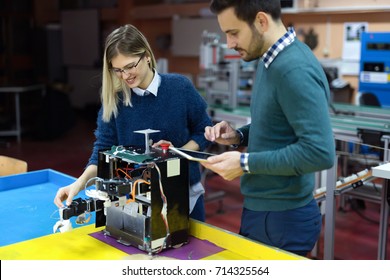 Young students of robotics preparing robot for testing