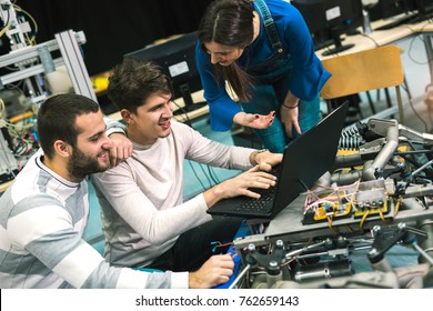 Young students of robotics preparing robot for testing in workshop