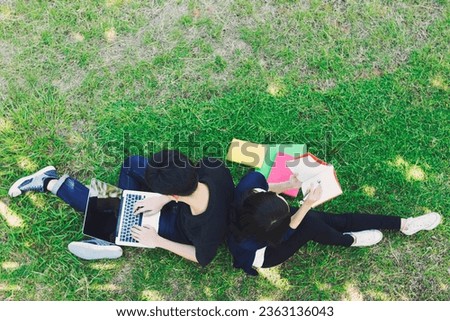 Young students siting on green grass and reading in top view. Education concept.