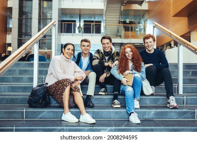 Young Students Smiling While Sitting On College Stairs. High School Students Sitting On Steps After Class.