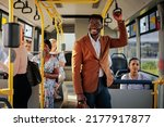 A young stylish african american businessman is smiling while riding the bus