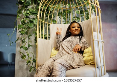 Young Stylish African American Woman In Gold Bird Cage Pose Indoor.