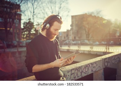 young stylish bearded man listening to music in the city
