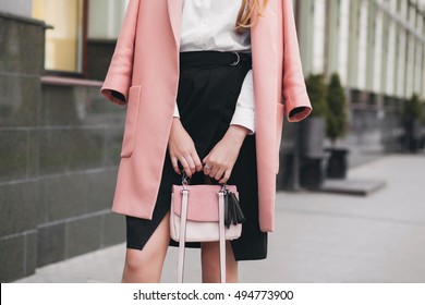 young stylish beautiful woman walking in street, wearing pink coat, holding purse, black skirt, fashion outfit, autumn trend,  accessories, hands close-up, details