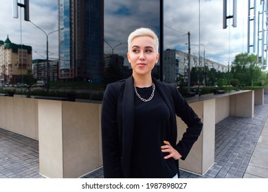 Young Stylish Business Woman With Short Hair And Nose Piercing. Confident Girl Look Like Lesbian Standing Near Business Center With Mirror Walls