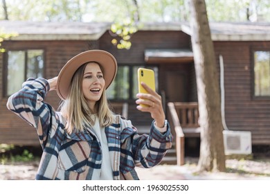 Young Stylish Caucasian Woman 30-35 Years Old Wearing Casual Clothing Shirt And Cowboy Hat. Influencer Using Social Media Via Mobile Phone. Person Enjoys Life At Morning During Summer Adventure In