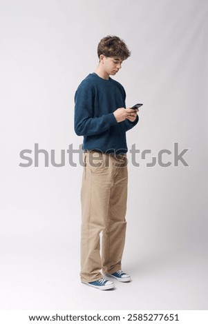 Young stylish guy checking messages on his smartphone, full body, isolated on white background