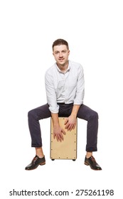 Young stylish guy sitting on the floor and holding a Cajon